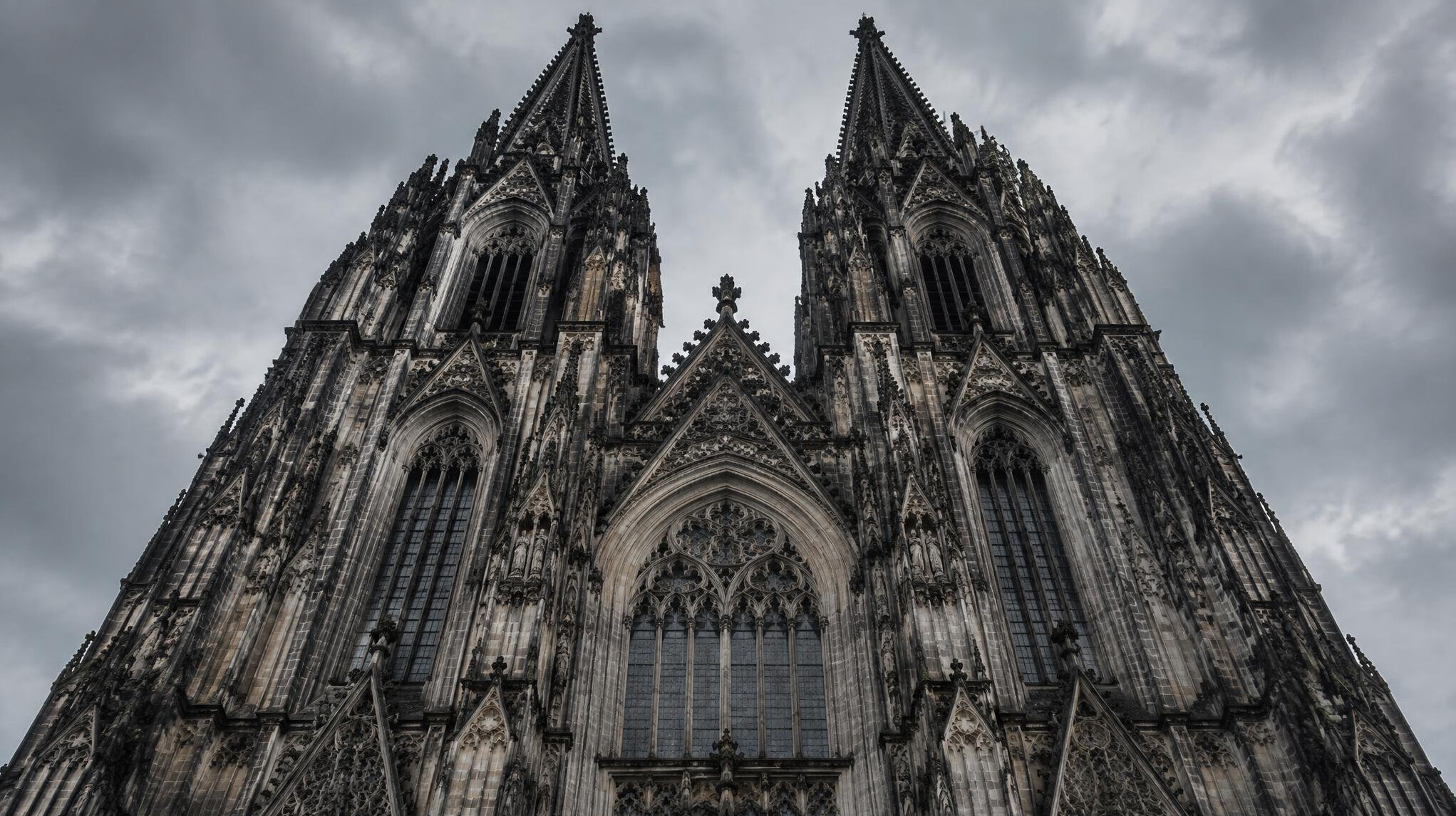 Gothic cathedral facade with twin spires against overcast sky
